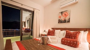 Una camera d'albergo con un letto grande, un balcone vista, un quadro appeso e un minibar.