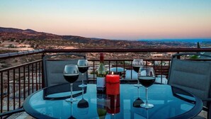 Un tavolo con quattro bicchieri da vino e una candela su un balcone con vista su un paesaggio suggestivo.