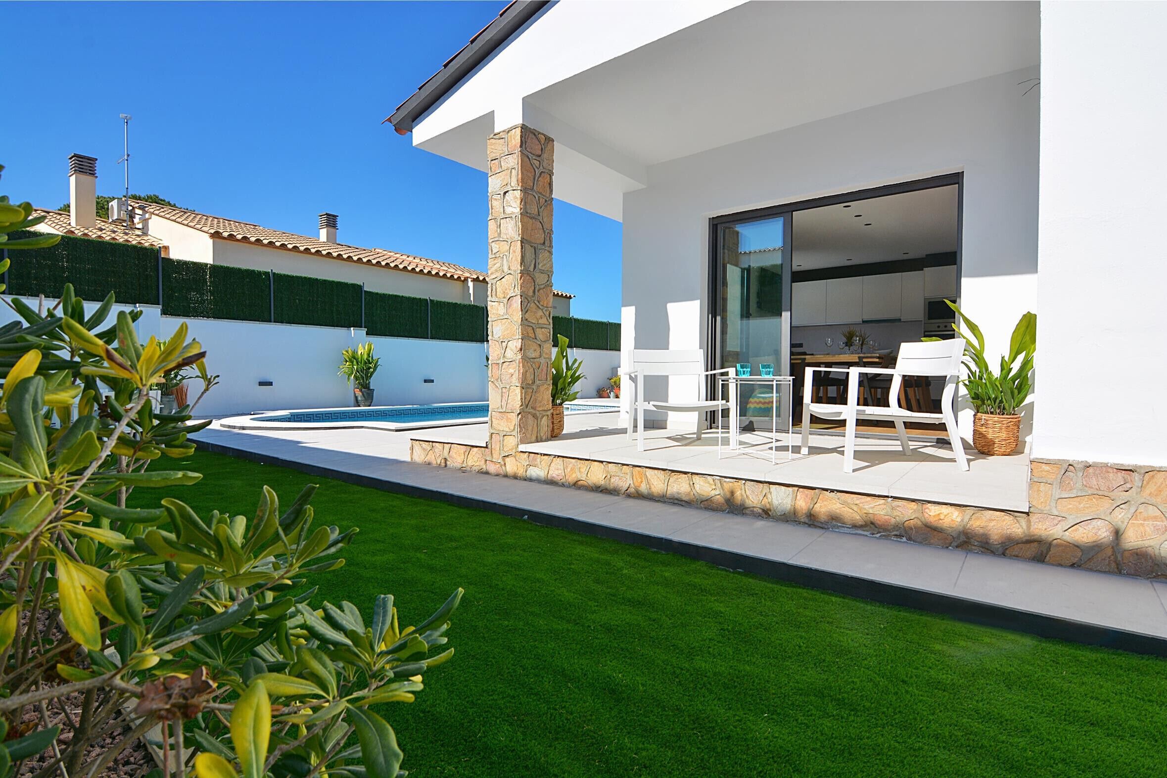 Et moderne hus med terrasse, pool og velholdt græsplæne.