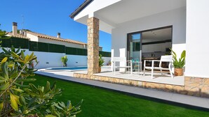Una casa moderna con patio, piscina y césped bien cuidado.