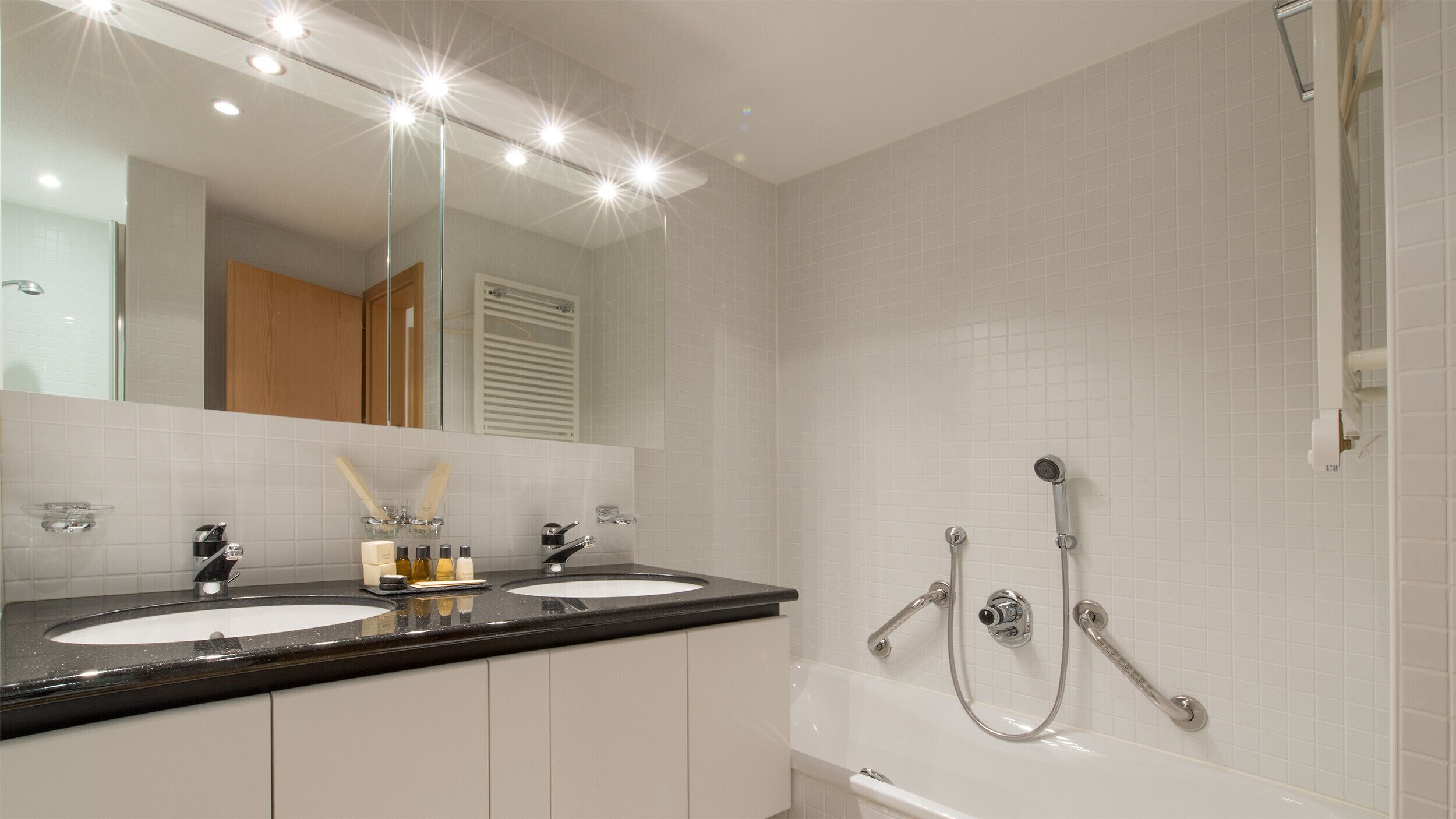 Een badkamer met twee wasbakken, een grote spiegel en een douche.
