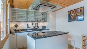 A modern kitchen with a central island, built-in cabinets, and a microwave.