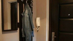Eine dunkle Holztür, ein schwarzer Schubladenschrank, ein Spiegel und eine hängende Jeansjacke.