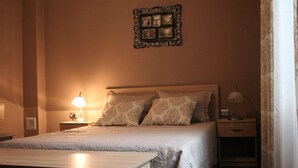 Ein ordentlich bezogenes Bett mit Kopfteil, zwei Nachttischlampen und einem an der Wand befestigten Bilderrahmen.