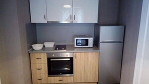 Eine kompakte Küche mit Mikrowelle, Backofen und Kühlschrank.