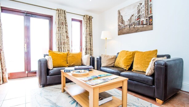 Een woonkamer met een bank, een salontafel en een schilderij aan de muur.