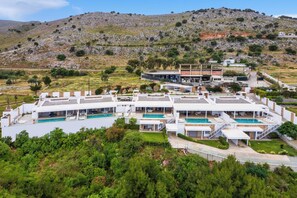 Eine moderne Villa mit mehreren Swimmingpools, einem angelegten Garten und einer Hügelkulisse.