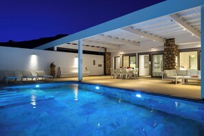 Ein überdachter Poolbereich mit Liegestühlen und einer Steinwand.