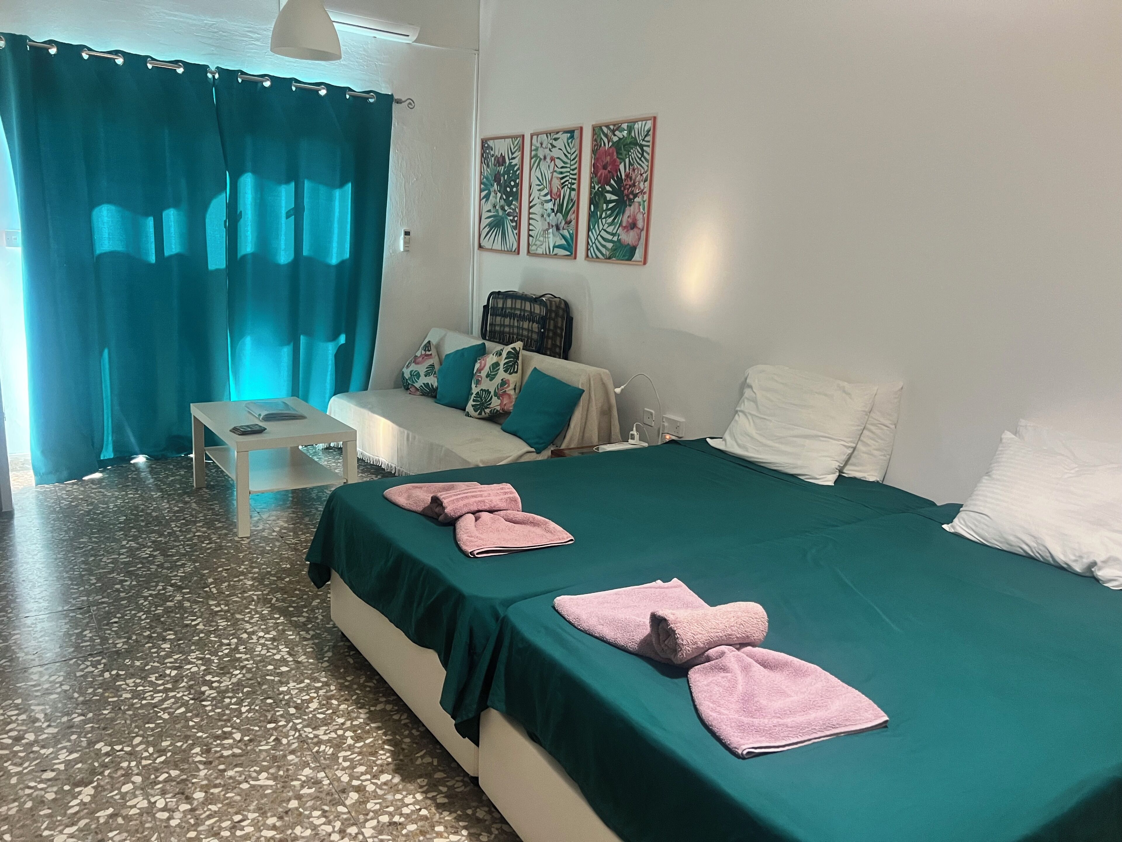Een hotelkamer met een bed, een kleine tafel, een stoel, een sofa en een raam met gordijnen.