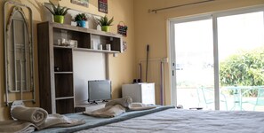Een kamer met een bed, een televisie, een kleine koelkast en een balkon met stoelen.