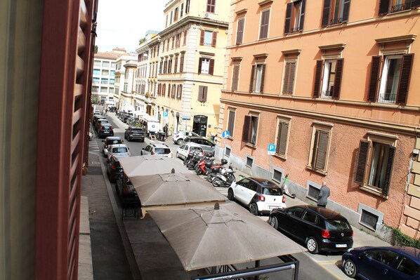 A street view with parked cars, a row of umbrellas, and buildings with multiple windows and balconies. - 50 Steps Colosseum Apartment (Roma)