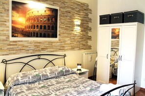 A bedroom with a bed, a nightstand, a wardrobe, and a picture of the Colosseum. - 50 Steps Colosseum Apartment (Roma)
