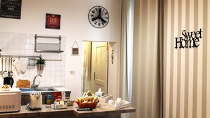 A kitchen with a clock, a sign reading "Sweet Home", and a basket of bread on the counter. - 50 Steps Colosseum Apartment (Roma)