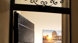 An open door leading to a room with a white sofa and a picture of the Colosseum on the wall. - 50 Steps Colosseum Apartment (Roma)
