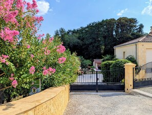 A gated entrance with a gravel path leading to a building with a tiled roof.