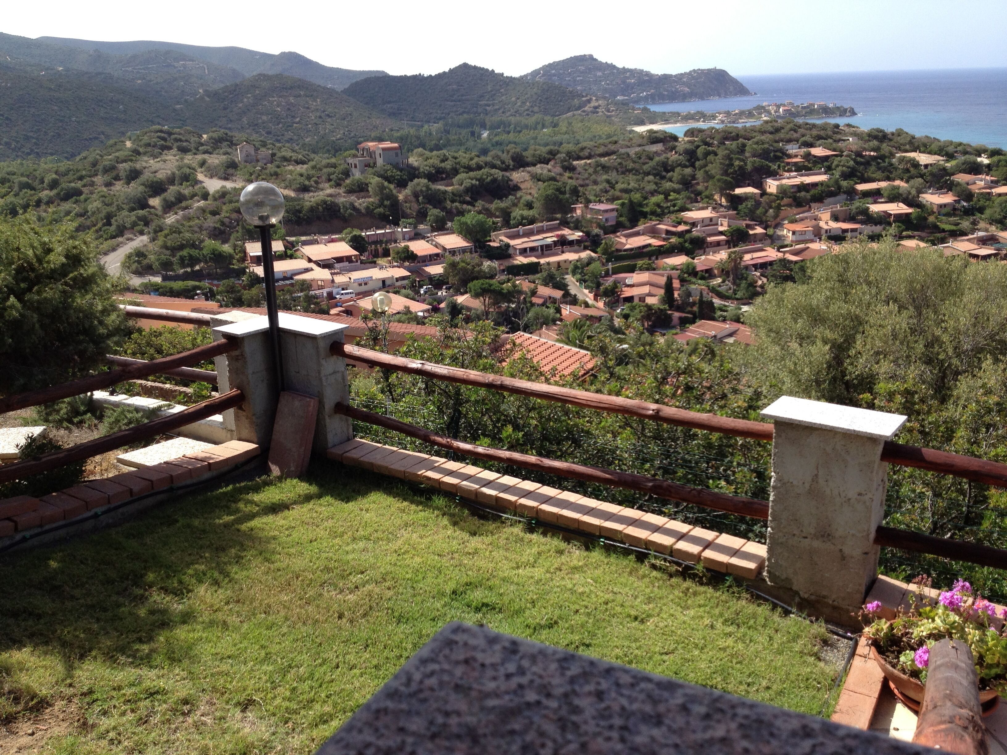 Une vue pittoresque d’un village côtier avec des maisons à étages, un ciel dégagé et une étendue d’eau visible au loin.