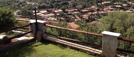Une vue pittoresque d’un village côtier avec des maisons à étages, un ciel dégagé et une étendue d’eau visible au loin.
