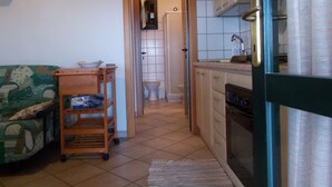 A compact kitchen with a sink, stove, and cabinets, leading to a bathroom with a toilet and shower. - Villa with sea view .. (Geremeas)