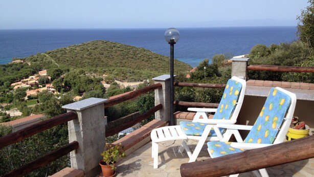 A terrace with two white lounge chairs with blue cushions, a potted plant, and a view of the sea and hills. - Villa with sea view .. (Geremeas)