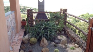 A garden with various cacti and succulents, a stone wall, and a view of the sea. - Villa with sea view .. (Geremeas)