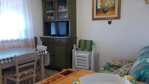A room with a dining table, chairs, a cabinet, a television, and a bed. - Villa with sea view .. (Geremeas)