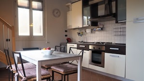 Una cocina con una mesa de comedor, sillas, estufa, horno y un reloj en la pared.