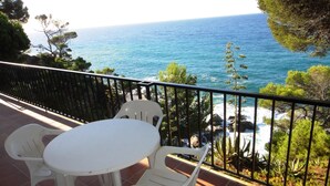 A balcony with a table and chairs overlooking a coastal view. - Comfortable apartments with pool facing the sea. Ref. Cala Llevadó-24 (Tossa del mar)