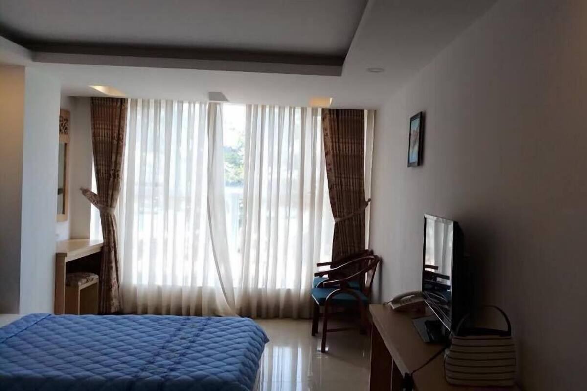 Une chambre d’hôtel avec un lit, un bureau, une chaise, une télévision et un tableau au mur.