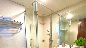 Une salle de bain avec une douche à parois de verre, des toilettes, un lavabo avec un miroir et une étagère avec des serviettes.
