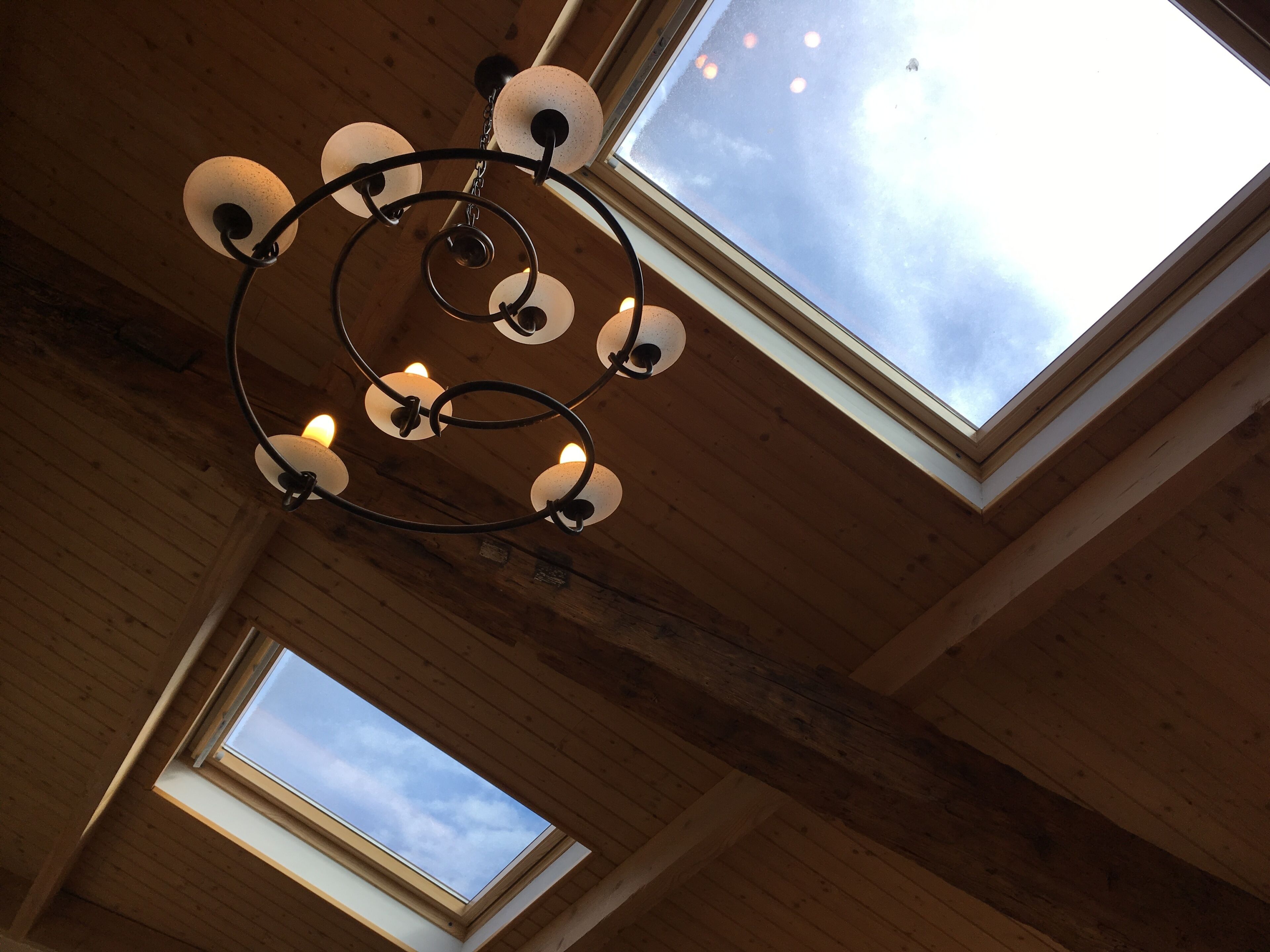 A ceiling with a circular chandelier and skylights.