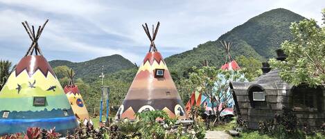 Colorful, uniquely designed yurts in a lush garden setting with a mountain backdrop.