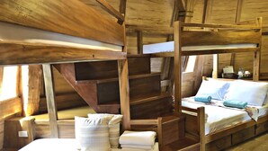 A rustic wooden cabin with bunk beds, a small table with cups and a menu, and a window providing natural light.