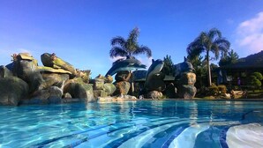 A pool with clear water, surrounded by large rocks and palm trees.
