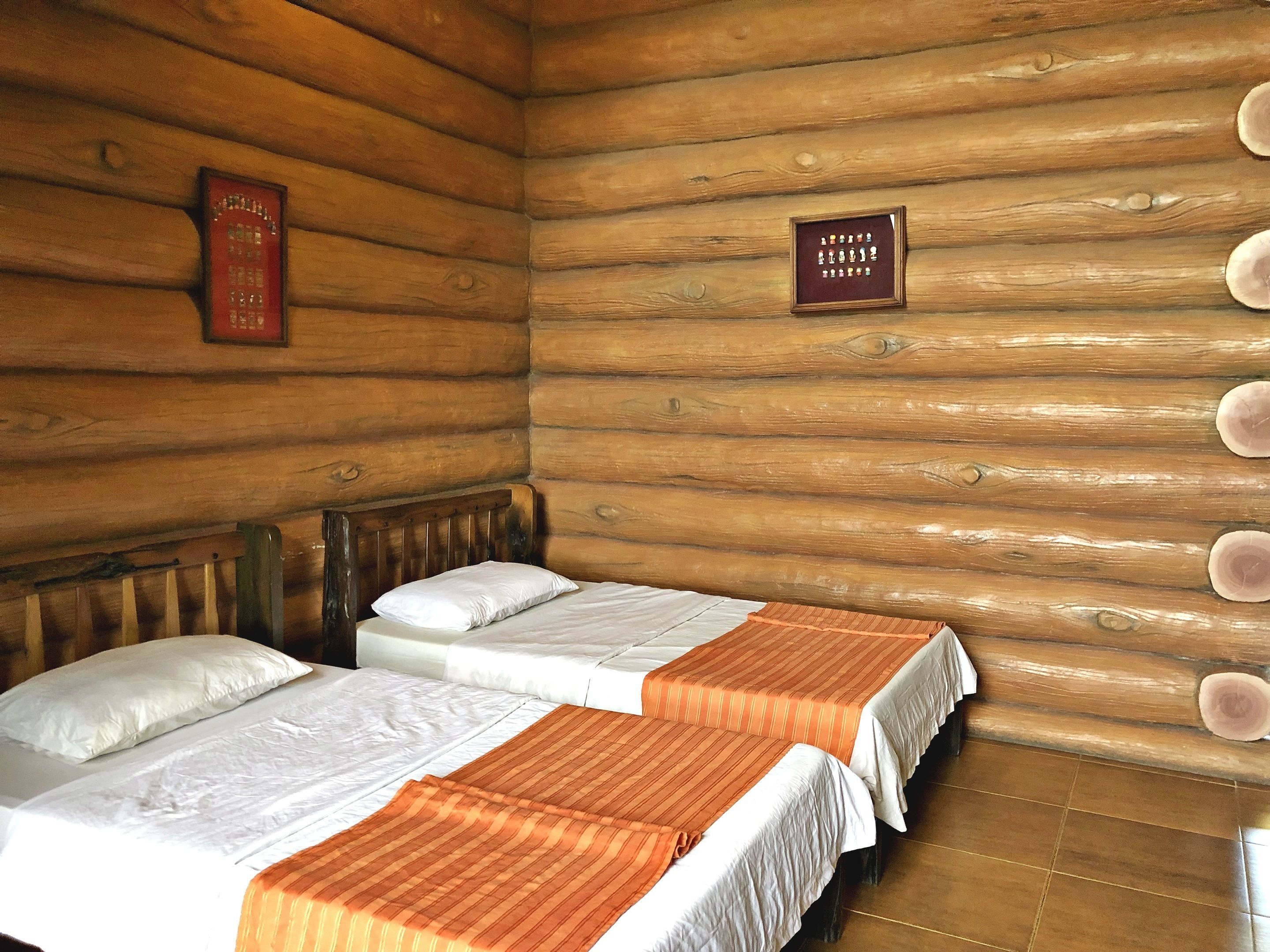 A log cabin room with two beds, wooden walls, and a framed sign on the wall.