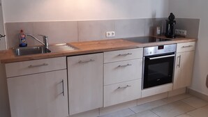 A modern kitchen with a stainless steel sink, a coffee machine, and a built-in oven. - Vacation home on the romantic road (Landsberg/Erpfting)