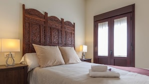 A neatly made bed with a wooden headboard, two bedside lamps, and a folded towel on the bed.