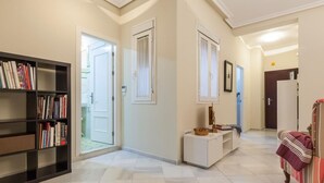 A spacious hallway with a bookshelf, a console table, and a cozy seating area.