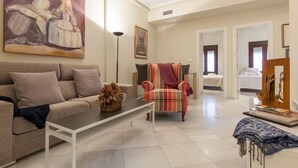A spacious living room with a sofa, a coffee table, and a chair. There is a painting on the wall and a doorway leading to another room.