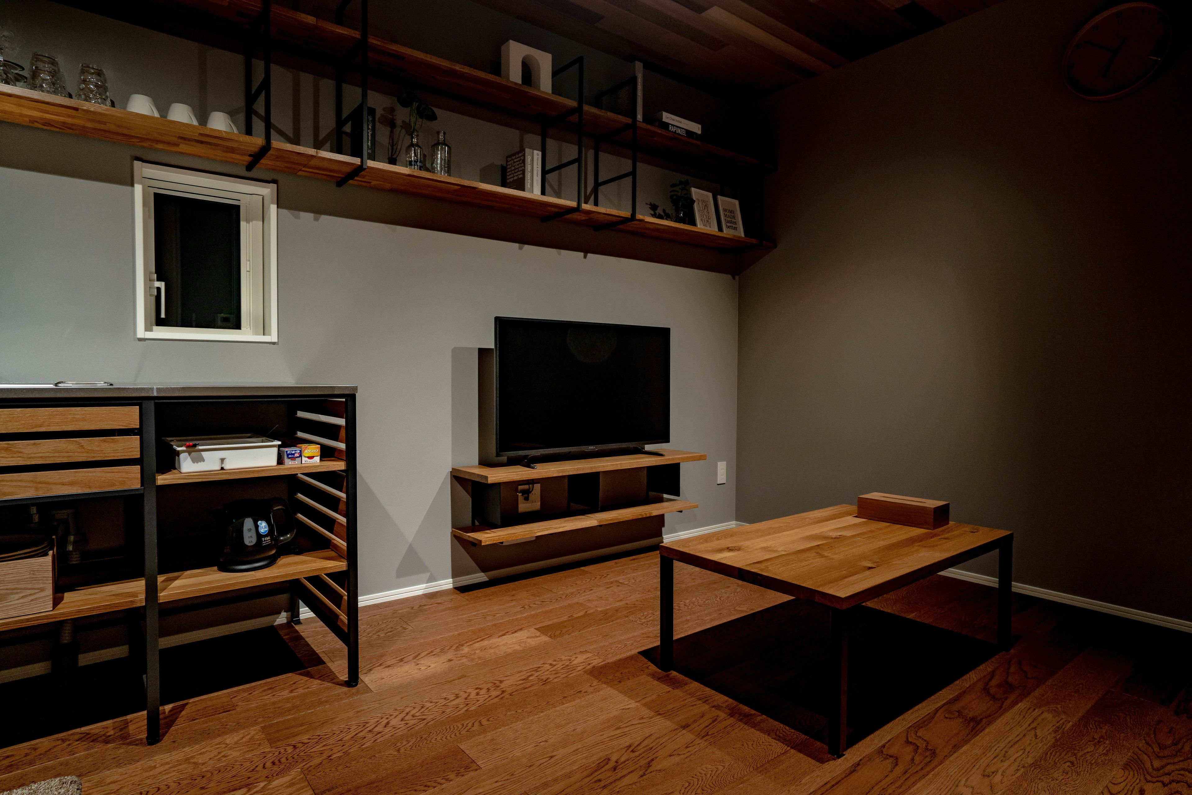 Una sala de estar moderna con suelo de madera, televisor de pantalla plana, estanterías empotradas y una mesa de centro.