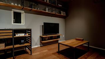 Una sala de estar moderna con suelo de madera, televisor de pantalla plana, estanterías empotradas y una mesa de centro.