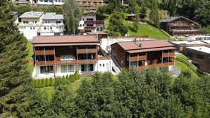 A cluster of modern multi-story buildings with balconies, surrounded by lush greenery and a hilly landscape.