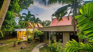 A tropical garden with a pathway leading to a house with a red roof. - Nakatani Villas By Lofty (Kamala)