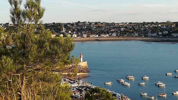 Une ville côtière dotée d’un phare, de bateaux et d’une côte rocheuse.