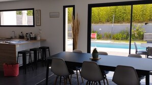 Une cuisine moderne avec un coin repas, de grandes fenêtres et une vue sur une piscine.