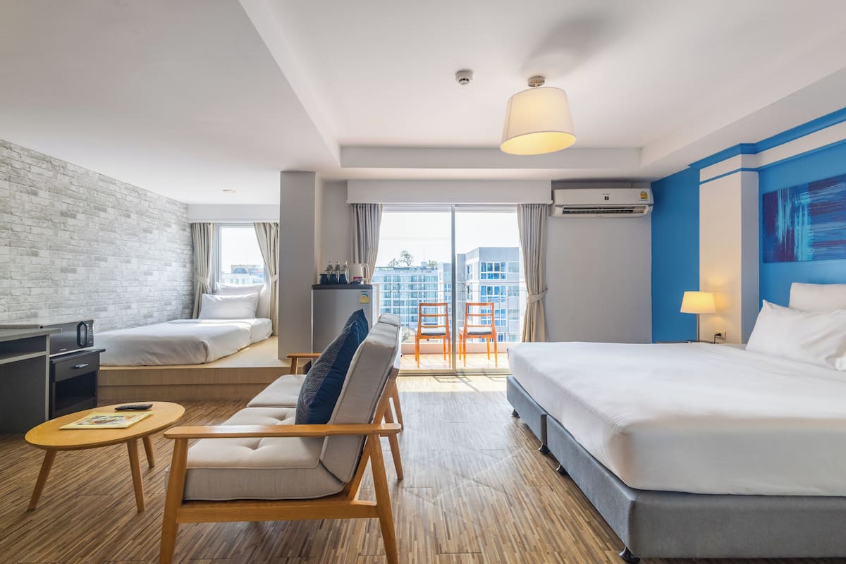Ein modernes Hotelzimmer mit einem großen Bett, einer Couch, einem Schreibtisch und einem Balkon mit Blick auf die Stadt.