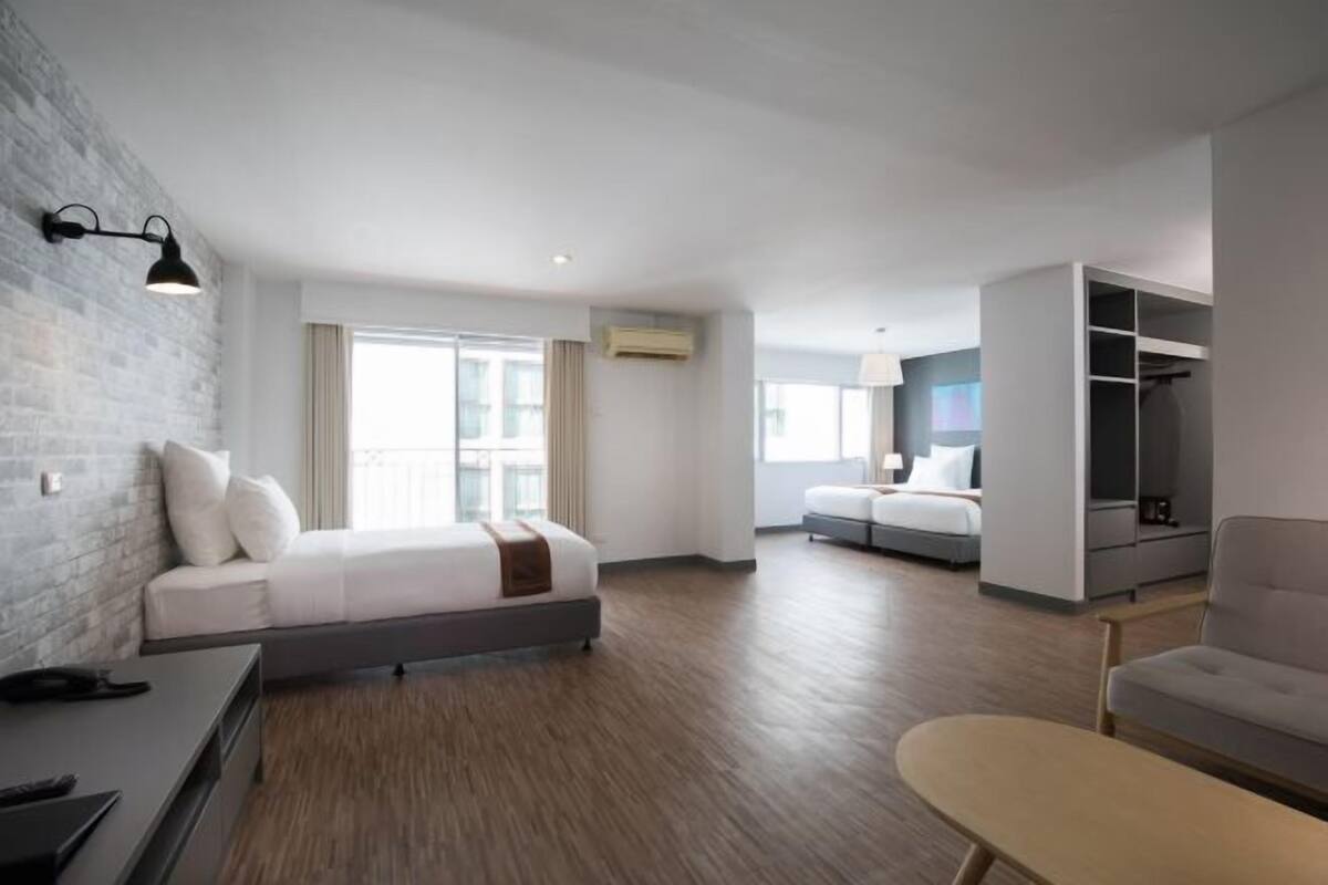 Ein modernes Hotelzimmer mit Bett, Sofa, Schreibtisch und Kleiderschrank.