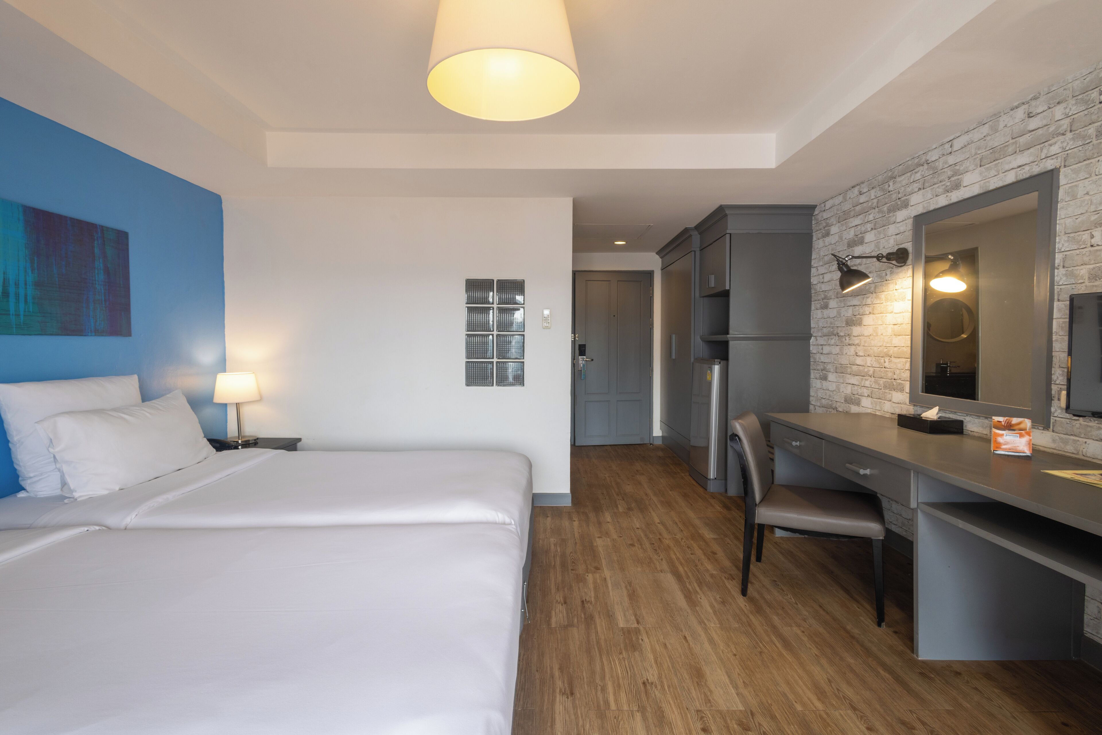 A hotel room with a bed, desk, and kitchenette.