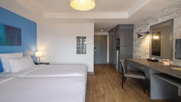 A hotel room with a bed, desk, and kitchenette.