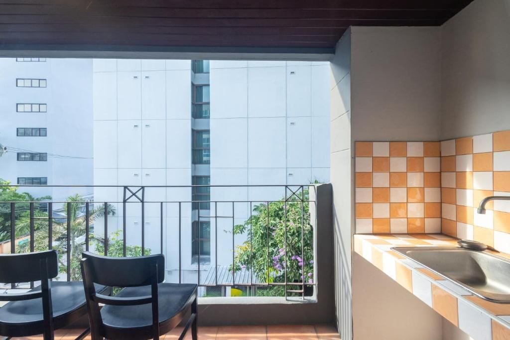 A balcony with two chairs and a view of a building.