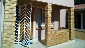 A house with a gated entrance, a brick column, and a small porch area. - BJ&T Vacation Homes (Kasane)
